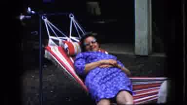 California USA (1969): Woman In Purple Pattern Dress Laying And Swinging In