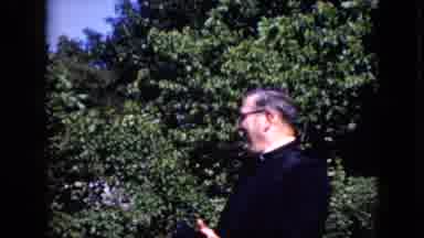 California USA (1969): Priest Standing In Front Of A Crowd Of People Talking To
