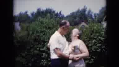 California USA (1969): A Couple Kissing In The Yard Of A House With Bushes And In