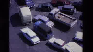 Loudes France (1969): Many Cars And Trucks Driving Through Intersection In