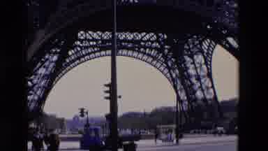 Paris France (1969): Traffic In Paris Driving Past The Eiffel Tower On A Busy Road