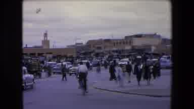 Algeria (1971): People Moving Through A Market By Foot And Automobiles