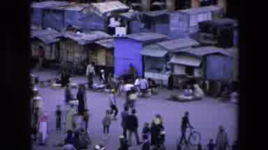 Algeria (1971): Crowd Of People Walking In An Open Market Near Small Huts