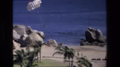 Mazatlan Mexico (1972): A Person Floats Down In Parachute Over A Beach As People