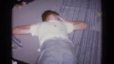New Jersey USA (1965): Boy Sleeping On Rug As Older Family Member Looks On From