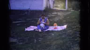 New Jersey USA (1965): A Family With Kids Sitting Outside The House On The Ground