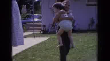 New Jersey USA (1965): A Boy Carries A Female Toddler In The Backyard Of A Home