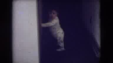 Athens Ohio USA-1966: Toddler Standing Near Wall Holding It, Sees Person Approaching
