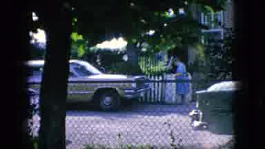 New Jersey USA-1966: Woman in Blue Dress at Picket Gate with Classic Station Wagon