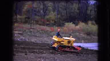 Ohio USA (1966): Man Driving A Yellow Bulldozer In Reverse And Waving