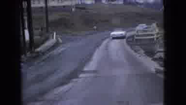 Ohio USA (1966): Cars Turning A Curb Road After Hitting Rough Bump Passing Dump