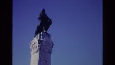 PORTUGAL-1972: Dark Statue On A White Pillar Set Against A Blue Sky
