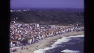 Portugal (1972): Waves Crashing Onto A Beach With The Town Just Beyond The