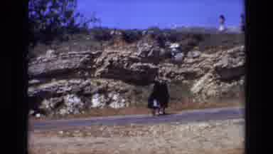 PORTUGAL-1972: Two Women in Black Dresses Walking on Road with Children Running on Hill