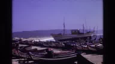 Portugal (1972): Boats Line The Shore Of An Ocean Village Where People Stroll