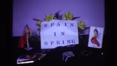 Spain (1972): Paper On Table Reading 'Spain In Spring' With Figurines And Flowers