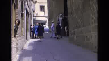 Spain (1972): People Exit A Building And Walk Down An Urban Alley In Daylight