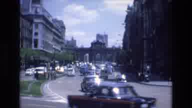 Spain (1972): Cars Passing Through A City While A Pedestrian In Uniform Waits