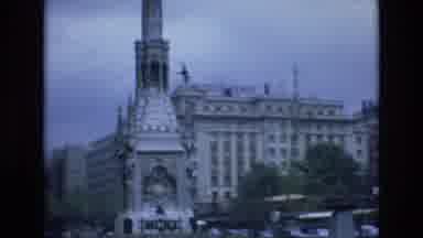 Spain (1972): Car Driving Fast Through European Town Showing Monument And Fields