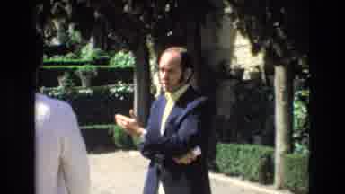 Spain (1972): Man Talking To Others Women Passing Shot To Buildings And Street