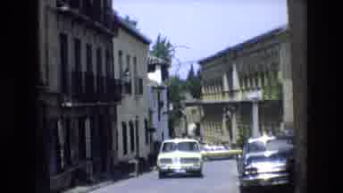 Spain (1972): A Street Lined With Buildings Has Cars Parked Along The Curb And