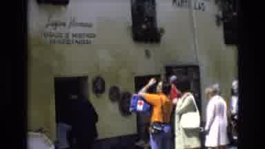 Spain (1972): People Taking Pictures And Walking Into A Building Which Has Text