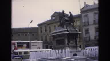 Spain (1972): Fountains Bubble Around Statue Set In City Square Vehicles Pass