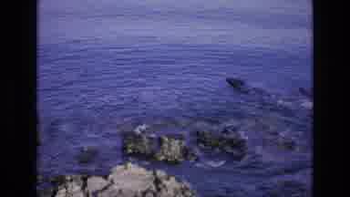 Spain (1972): Woman Walking By Ocean Towards White Buildings In Distance