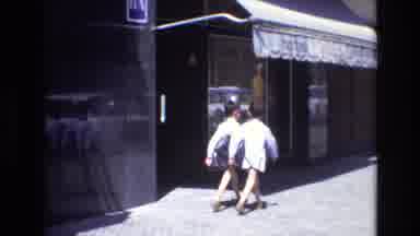 Spain (1972): Two Young Boys Walk Down The Street Lined With Palm Trees