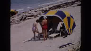 Cuba (1956): Two Women At A Cabana On The Beach While One Rubs Suntan Lotion On