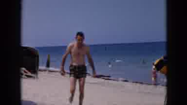 Cuba (1956): Man Walking Up The Beach Past Yellow And Blue Umbrella Daytime
