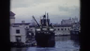 Cuba (1956): Large Ships Docked In Harbor And Man Turning To Camera And Smiling