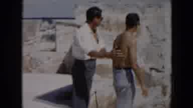 Cuba (1956): Man Directing Shirtless Man Around Stone Walls Outside