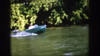 Virginia USA (1958): A Man Steers A Motorboat Near A Trees Bordering A Body Of