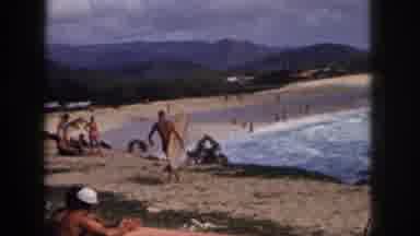 Hawaii USA (1959): Surfer Walks The Shore As The Wave Crashes To The Beach Full Of