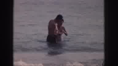 Hawaii USA (1959): Older Couple Lovingly Wade In The Ocean Enjoying The Waves