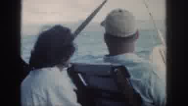 Oahu Hawaii USA (1959): Two Fishermen Aboard A Boat Sailing Past A Small Sailboat