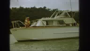 Michigan USA (1961): Man Wearing Hat Carrying Child On The Hull Of A Boat Moving