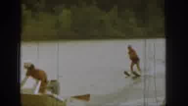Michigan USA (1961): Person Water Skiing On Lake Behind Boat With Trees In The
