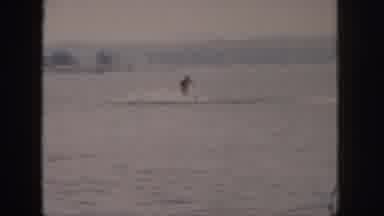 Michigan USA (1961): Person Water Skiing On A River With A Bridge Connecting Two