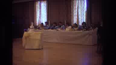 Boston USA (1974): Several People Are Sitting At A Long Table Eating Together At A