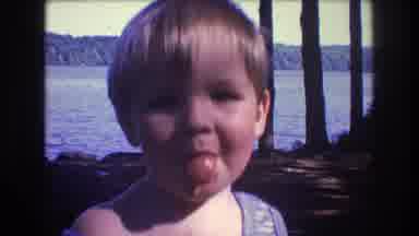Baxter Maine USA (1975): Small Boy Makes Faces At The Camera With Trees And Lake