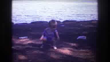 Baxter Maine USA (1975): A Blonde Child Having Fun With An Object By A River