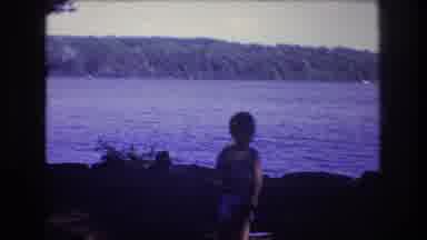 Baxter Maine USA (1975): Child Playing With His Back To A Lake While A Person