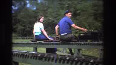 Baxter Maine USA (1975): A Young Man And Woman Riding A Medium Sized Train Smiling
