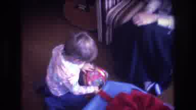 Baxter Maine USA (1975): Little Kid Sitting On The Ground Opening Up A Present