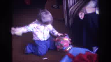 Baxter Maine USA (1975): Young Child Excitedly Unwrapping Ball From Holiday
