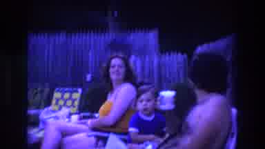 Boston USA (1975): Man Peeking Over Fence At Man Woman And Child By The Pool