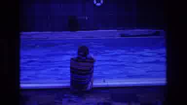 Boston USA-1975: Old Film Of A Person Sitting Near A Pool Wearing A Striped Shirt