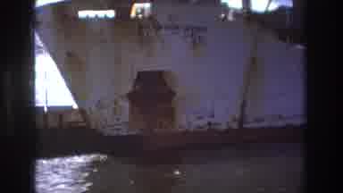 Boston USA (1975): People On A Small Speedboat Go By A Large Ship By The Shore